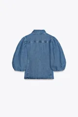 Blusa de denim con cuello solapa y manga abullonada por debajo del codo. Cierre frontal con botones.