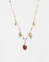 Collar corto dorado con cadena de eslabones y dijes colgantes: fresa roja, corazón, hongo y strass.