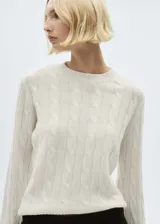 Sweater color crema de punto trenzado, con cuello redondo y mangas largas.