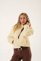 Campera color manteca con diseño acolchado de flores, cuello alto, cierre frontal con cremallera y bolsillos laterales.