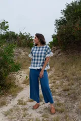 Top de tela a cuadros azul y blanco, con corte cuadrado, mangas cortas con volados y ruedo con volados.