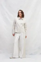 Chaqueta color crema de lino, de corte recto, con cuello camisero y cierre frontal con botones.