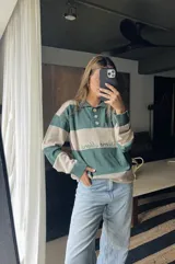 Sweater de hilo de algodón a rayas horizontales rosas y grises, con cuello polo, botones de guampa y bordado de Sierra Mora a tono.