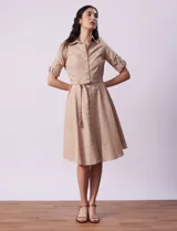 Vestido camisero blanco de algodón con cuello con solapa, delantera abotonada, mangas 3/4 regulables con presilla y botón, y cintura con lazo de ajuste.