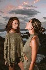 Poncho tejido color verde oliva con brillos dorados, de corte amplio y mangas murciélago. Incluye short haciendo juego.