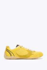 Zapatillas deportivas amarillas con detalles en gamuza y malla, cordones blancos y suela color caramelo.