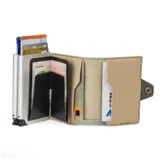 Billetera doble de cuero marrón con detalles en rosa. Cuenta con doble caja de aluminio con sistema de deslizamiento para tarjetas, clip para billetes y espacio adicional para documentos.