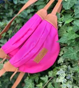 Riñonera fucsia de lona con correa regulable y detalles en cuero vacuno color marrón. Cuenta con bolsillo interno con cierre y bolsillo externo en la parte trasera.