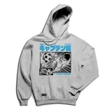 Buzo canguro gris con capucha y cordones ajustables. Estampado frontal con imagen de la serie animada Supercampeones y texto en japonés.