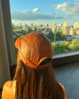 Gorra de cuero marrón con visera y logo bordado en el frente.