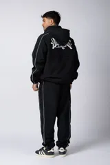 Campera negra con cierre frontal, capucha y ribetes blancos. Presenta el logo 'Club Vop' en el pecho y una ilustración de hongos psicodélicos en la espalda.