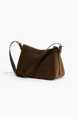 Cartera marrón de gamuza sintética con correa de hombro ajustable y cierre superior con cremallera.