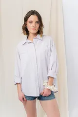 Camisa color crema de algodón liviano, calce oversize, con cuello camisero, cierre abotonado, mangas largas con opción de arremangado y dos bolsillos frontales con solapa.