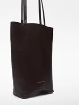 Bolso tipo shopper vertical de cuero color marrón oscuro, con asas largas para el hombro, base rígida curvada, un compartimento y bolsillo interior.