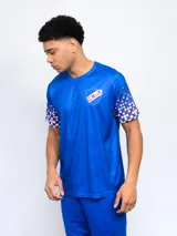 Remera deportiva azul con el escudo del Club Nacional de Football en el pecho y diseño de cuadros rojos y blancos en las mangas.