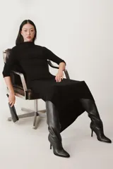 Vestido negro de lana con cuello alto, mangas largas y bajo asimétrico.