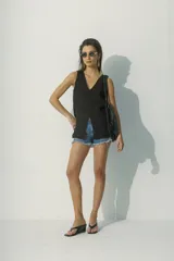 Blusa negra sin mangas con escote en V y abertura en el centro.