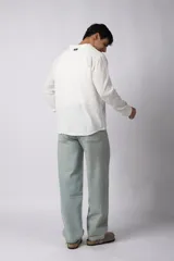 Camisa de lino blanca de manga larga, con cuello clásico y cierre frontal con botones. Corte recto y holgado.