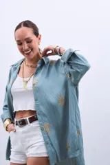 Camisa celeste con bordado de hojas color dorado, de corte holgado y manga larga con puños abotonados.