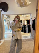 Sweater de punto color beige con cuello alto, mangas largas y corte holgado. Presenta tajos laterales y bordados florales en puños y cadera.