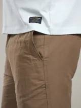 Bermuda color beige claro, de corte casual y largo por encima de la rodilla, con bolsillos laterales.