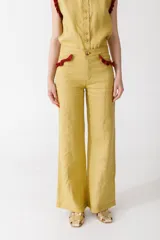 Pantalón de jean azul oscuro, de corte acampanado, con bolsillos delanteros con detalle de volados.