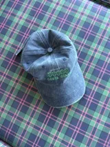 Gorro tipo jockey de tela denim azul gastado, con visera curva y bordado frontal en hilo verde que dice "COSTA DULCE".