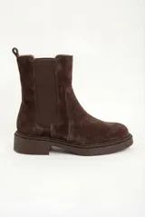 Bota tipo Chelsea de gamuza color marrón oscuro, con paneles elásticos laterales al tono, tirador trasero y suela de goma robusta con vira pespunteada.
