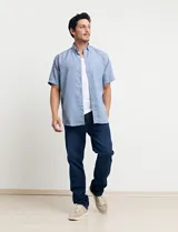 Camisa celeste con microestampado geométrico, de corte clásico, manga corta, cuello abotonado y bolsillo en el pecho.