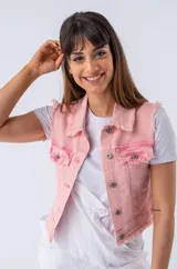 Chaleco de jean rosa con cuello clásico, cierre frontal con botones metálicos, dos bolsillos frontales con solapa y detalle de flecos en el ruedo y las sisas.