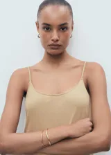 Mono largo color beige, de tirantes finos y corte recto. Incluye cinturón ancho de cuero marrón con hebilla plateada.