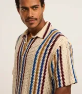 Camisa de manga corta con cuello alto y abotonada, confeccionada en ganchillo rústico con textura.