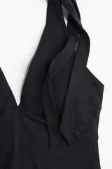Traje de baño negro de una pieza, con escote en V, breteles con moños y copas con relleno extraíble.