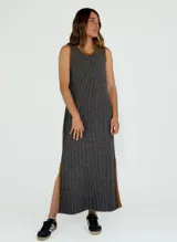 Vestido largo a rayas verticales en tonos grises y negros, con cuello redondo y sisas ribeteadas en marrón. Presenta aberturas laterales en el ruedo.