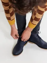 Botas de cuero azul marino con cordones y suela de goma color caramelo. Diseño clásico con costuras a la vista y dos pares de cordones.