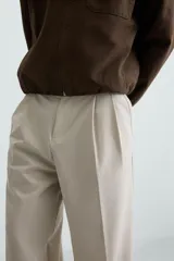 Pantalón de vestir color beige, corte wide fit, con cintura elástica, pliegues frontales, bolsillos laterales y traseros de vivo.