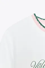 Camiseta blanca de algodón con cuello redondo y detalle de tricot a contraste en azul marino. Estampado frontal con texto "Estate sulla Costiera Amalfitana" en azul marino.
