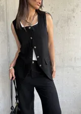 Chaleco negro de lino con botones dorados, corte entallado y bolsillos frontales.