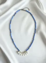 Collar corto con cuentas de vinilo azul y detalles de cristal azul y metal plateado. Presenta un colgante central con forma de abanico de cuentas blancas.
