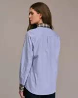 Camisa celeste a rayas verticales blancas, de corte recto, manga larga y cuello clásico con interior a cuadros.