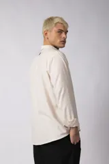 Camisa de manga larga color beige claro, con cuello abierto y calce relajado.