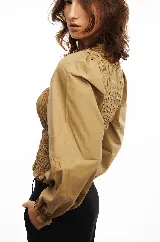 Blusa blanca de algodón con frunces tipo smock en el cuerpo, cuello redondo y mangas largas abullonadas con puños elásticos.