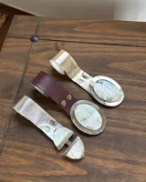 Cinto de ecocuero con hebilla redonda de alpaca y nácar.