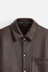 Sobrecamisa marrón de efecto piel con interior de borreguillo combinado a tono, de corte relaxed fit, cuello solapa, manga larga con puños abotonados, bolsillos de plastrón en pecho y laterales en cadera, efecto lavado y cierre frontal con botones a presión.