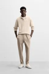 Pantalón negro de corte cropped, con cintura elástica ajustable con cordón, bolsillos laterales y traseros de vivo. El bajo tiene terminación con vuelta.