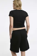 Short deportivo negro con cintura elástica y bolsillos laterales. Corte holgado a la rodilla.