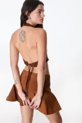 Top corto marrón de cuero con escote halter y espalda descubierta.