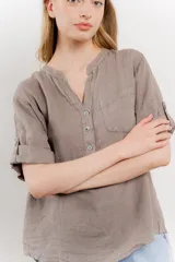 Camisa azul de lino con escote en V abotonado, bolsillo frontal y mangas 3/4 con trabilla.