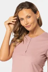 Remera color beige de corte clásico, con cuello redondo y mangas cortas. Presenta una botonadura frontal parcial con botones personalizados.
