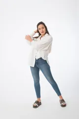 Camisa blanca de broderie con puños elásticos y botones frontales, de corte holgado.